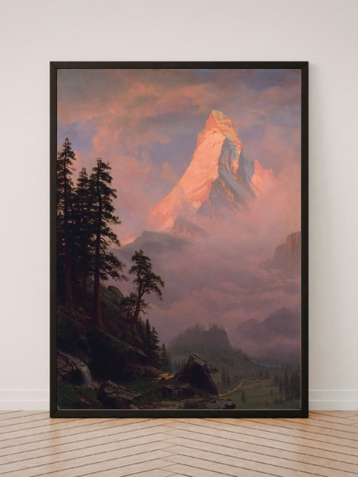 Sunrise on the Matterhorn art print in a black frame, leaning against a white wall on a wood floor