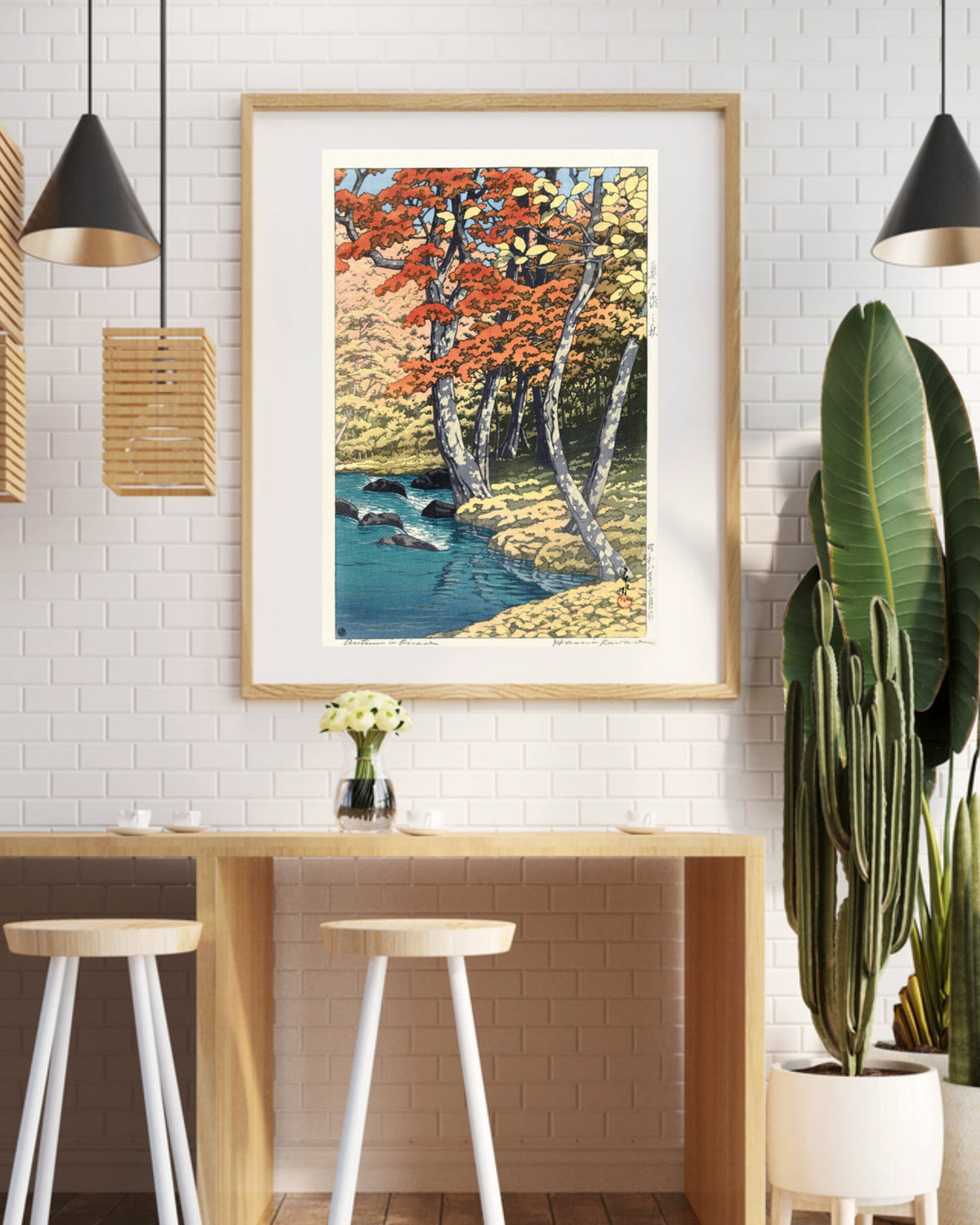 Lyrea art print in a black frame above a coffee shop counter with a white brick wall and pendant lights