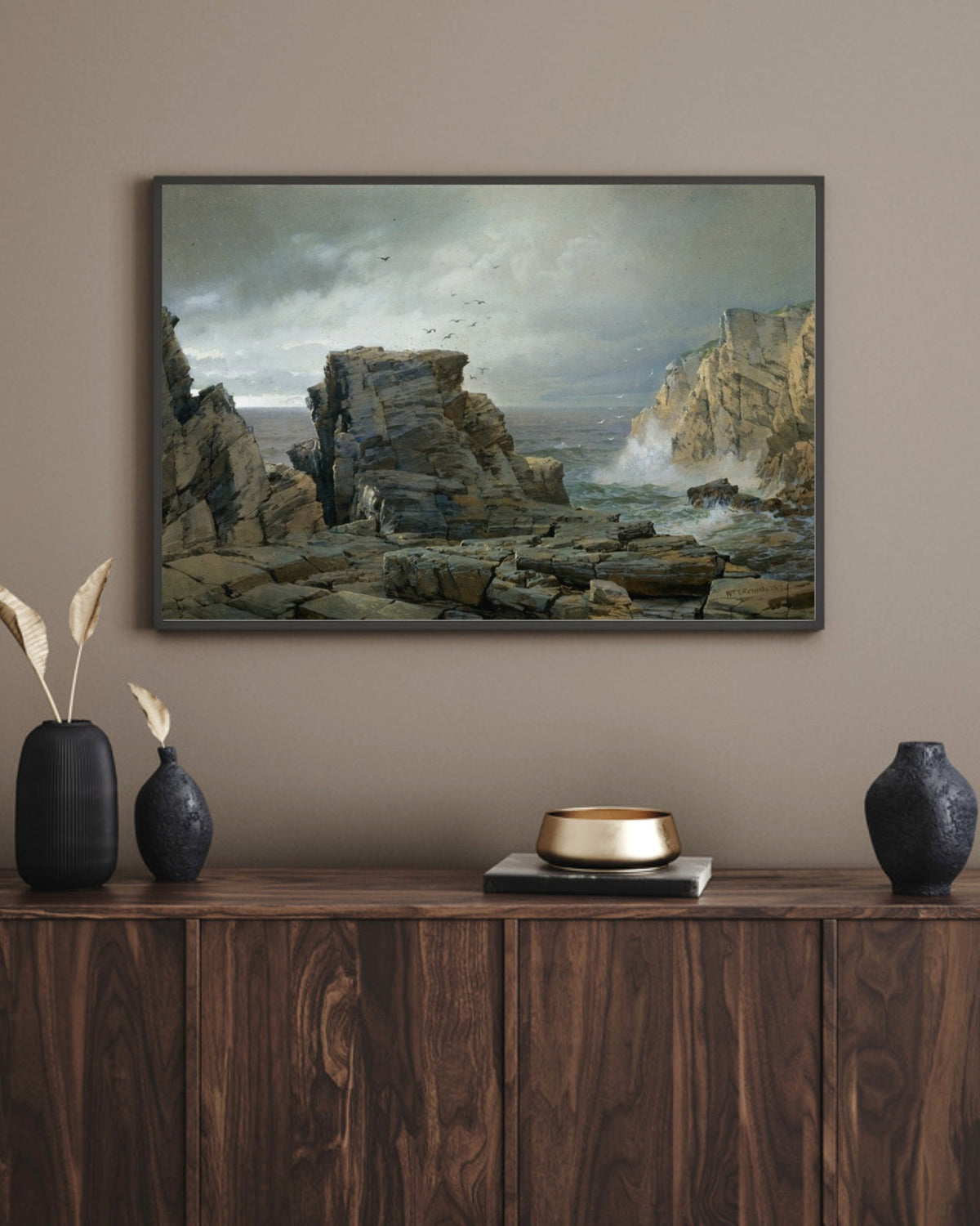 A Rocky Coast art print in a black landscape frame above a walnut sideboard