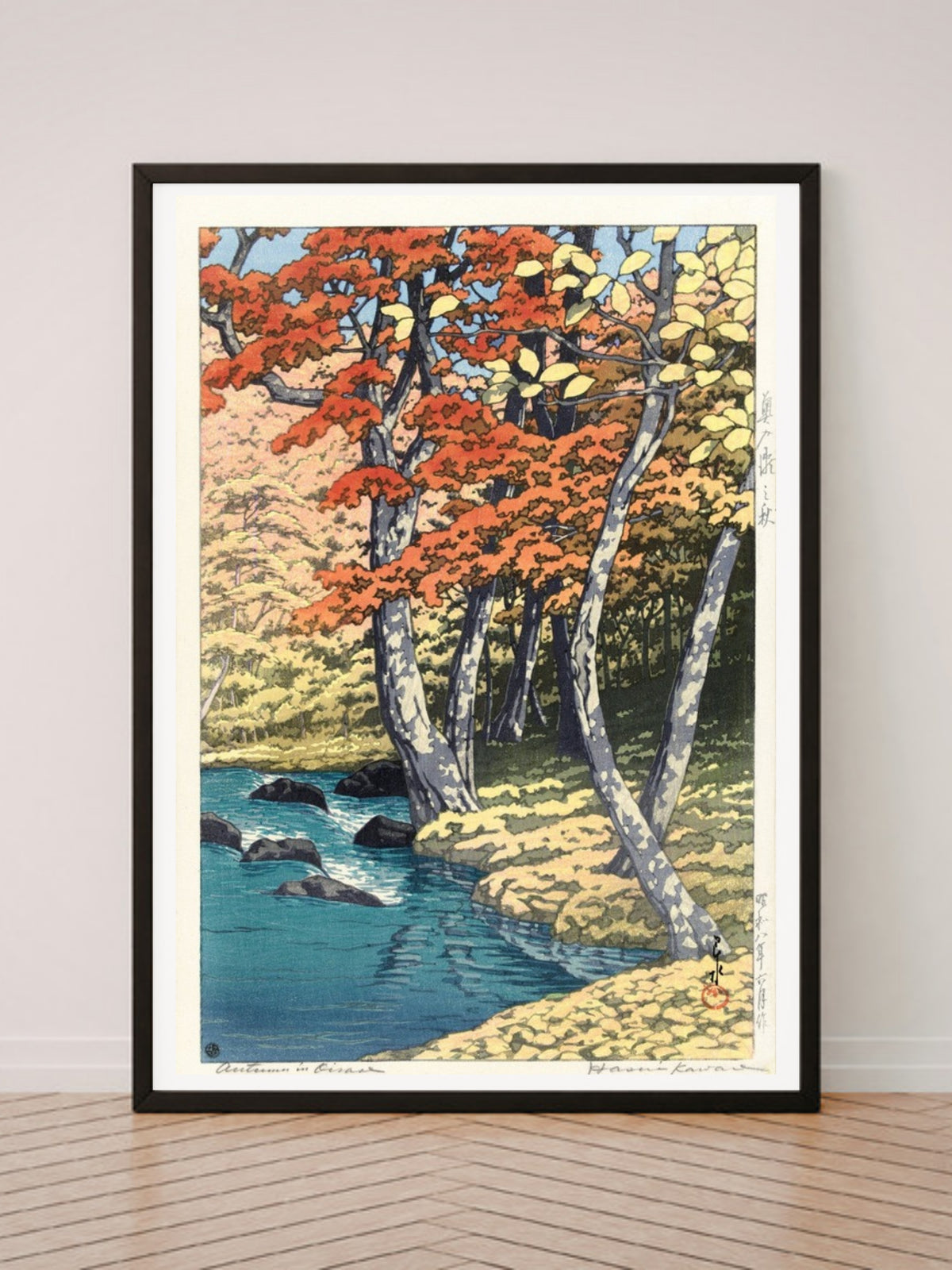 Herfst in Oirase art print in a black frame, leaning against a white wall on a wood floor