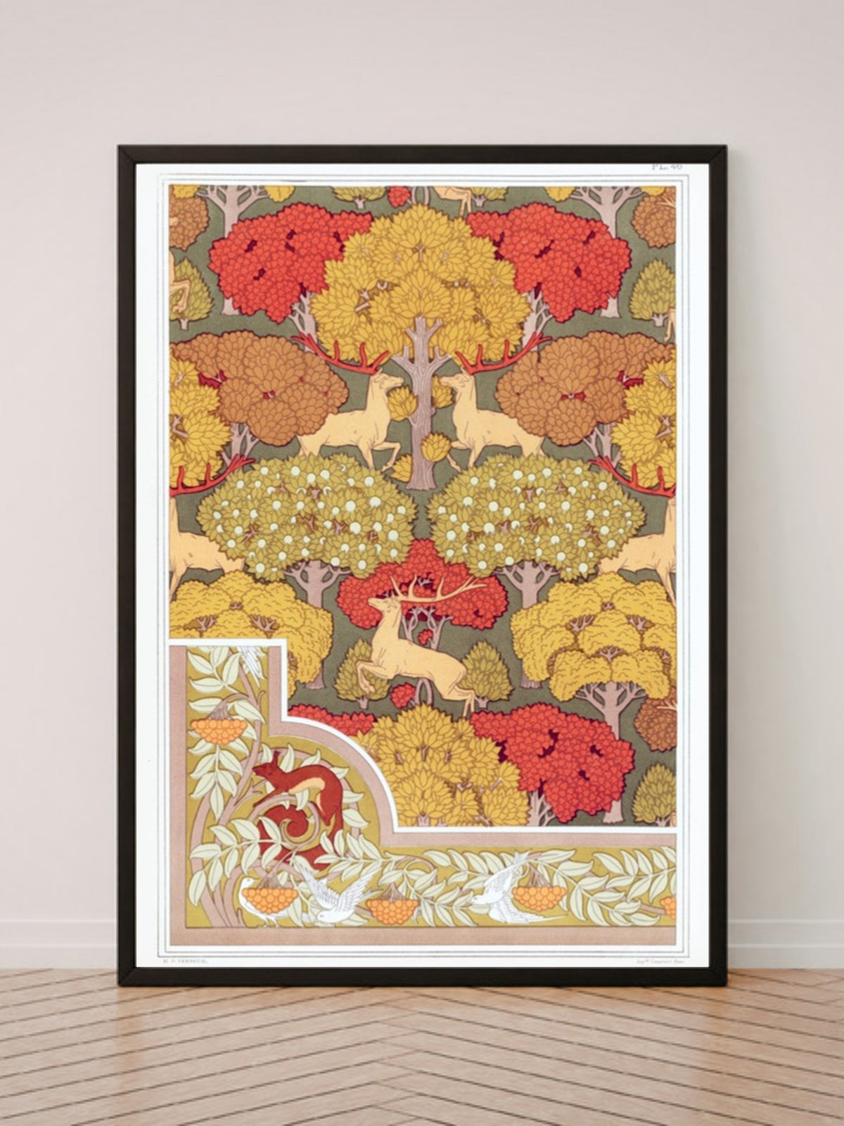 Cerfs et arbres art print in a black frame, leaning against a white wall on a wood floor