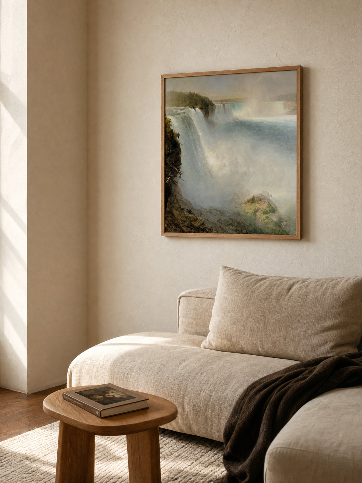 Niagara Falls by Frederic Edwin Church in a natural oak frame above a linen sofa in a sunlit living room.